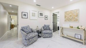A modern living room with two patterned armchairs, a small side table, and a console table with decorative items. - Close to the Beach and 5th Ave! Fun Naples Peaceful Getaway 4U!  (Naples)