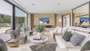 A modern living room with a large window, a sofa set, a coffee table, and a TV mounted on the wall. - Villa Almost Heaven by Vacation Marbella (Nueva Andalucía)