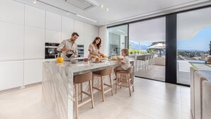 A modern kitchen with a marble island, stainless steel appliances, and a large window overlooking a scenic landscape. - Villa Almost Heaven by Vacation Marbella (Nueva Andalucía)