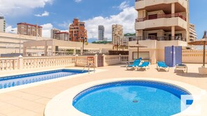 A rooftop pool area with lounge chairs and a swimming pool.