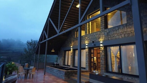 A modern building with a stone facade and large windows. - Leopard Rock Wilderness Resort Ooty by VOYE HOMES (Ootacamund)