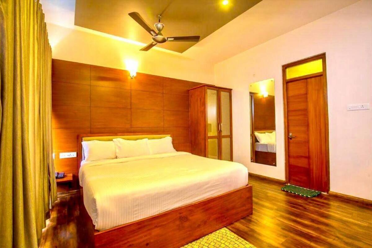 A bedroom with a wooden headboard, a bed with white linens, a ceiling fan, and a door with a mirror.