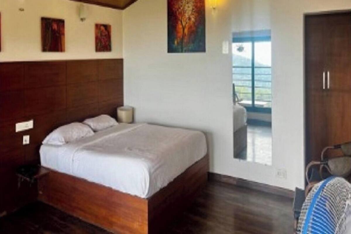 A bedroom with a wooden ceiling, a large bed, a nightstand, and a window with a view.