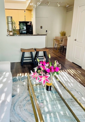 Un salon moderne avec une table basse en verre, un canapé et un coin repas avec des chaises.