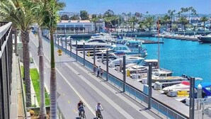 A marina with boats docked, a pedestrian walkway, and palm trees. - New Marina Del Rey 1 BDR Beach / Pool & Hot Tub, Ocean
 (Marina del Rey)