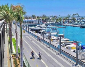 A marina with boats docked, a pedestrian walkway, and palm trees. - New Marina Del Rey 1 BDR Beach / Pool & Hot Tub, Ocean
 (Marina del Rey)