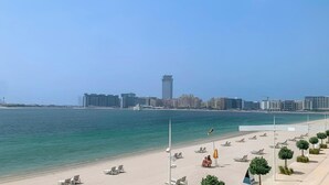 Una spiaggia con file di lettini e una vista chiara sullo skyline di una città sullo sfondo.