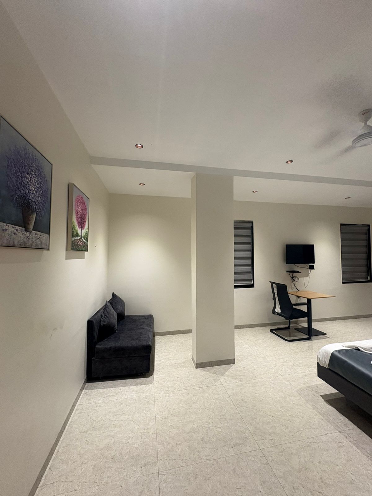 Una habitación moderna con sofá, un escritorio y una silla, televisión y obras de arte en las paredes.