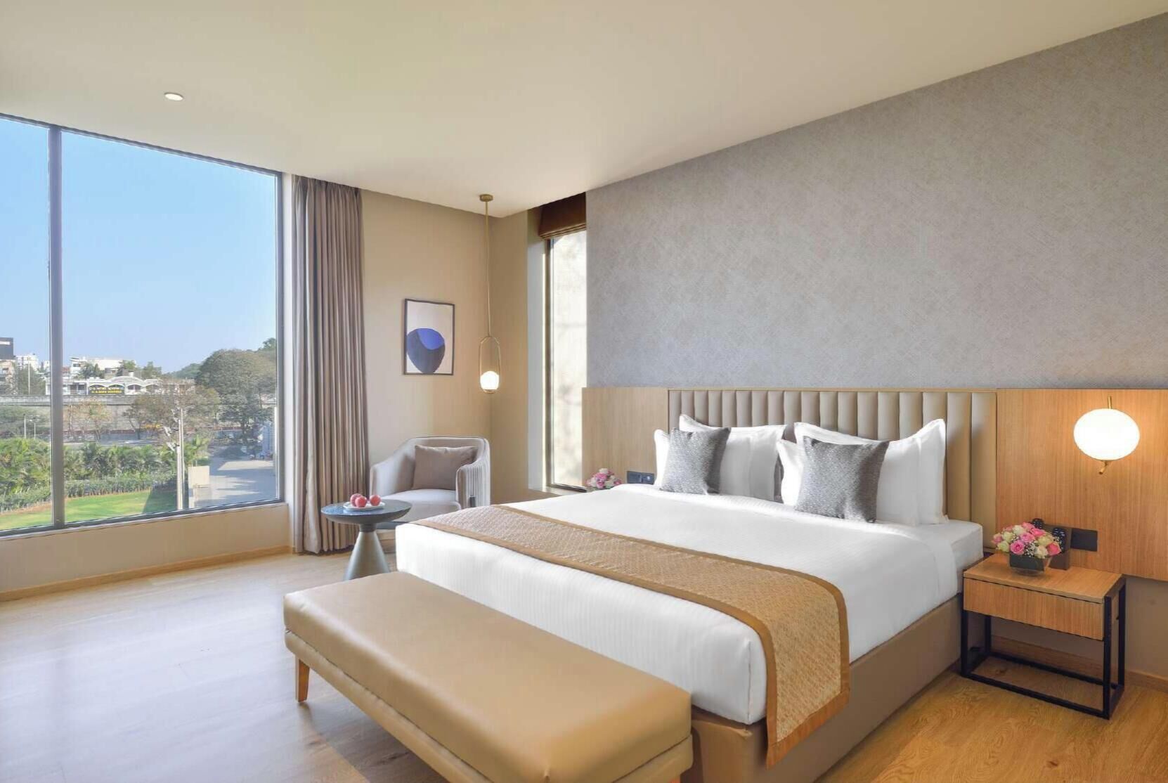 Une chambre d’hôtel moderne avec un grand lit, une banquette, une petite table et une table de chevet.