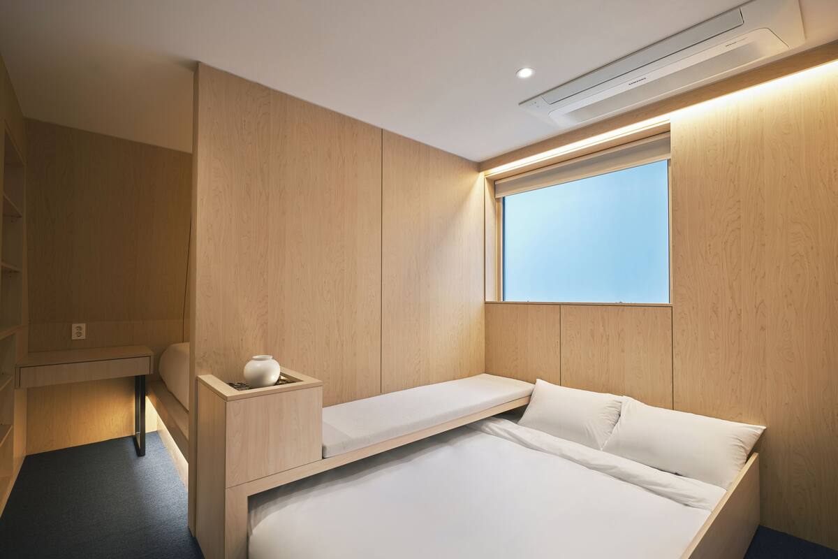 Una habitación pequeña con una cama, un escritorio y una ventana.