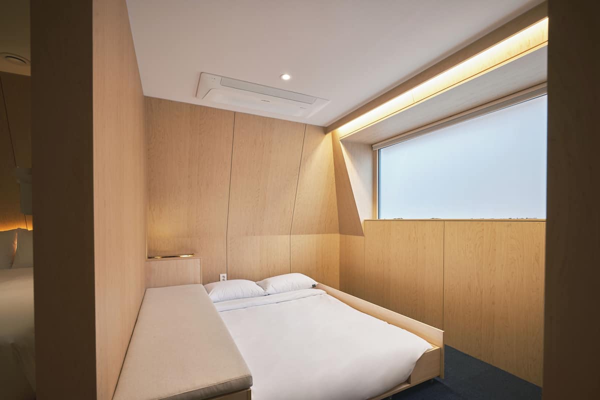 Un dormitorio moderno con cama, mesita de noche y ventana con vistas.