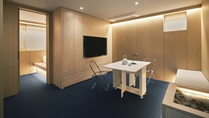 A modern room with a flat-screen TV mounted on the wall, a small table with chairs, and a built-in aquarium. - Dandelion Sinsa Branch 1 (Seoul)