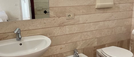 Une salle de bain équipée d’un lavabo, d’un bidet et de toilettes.