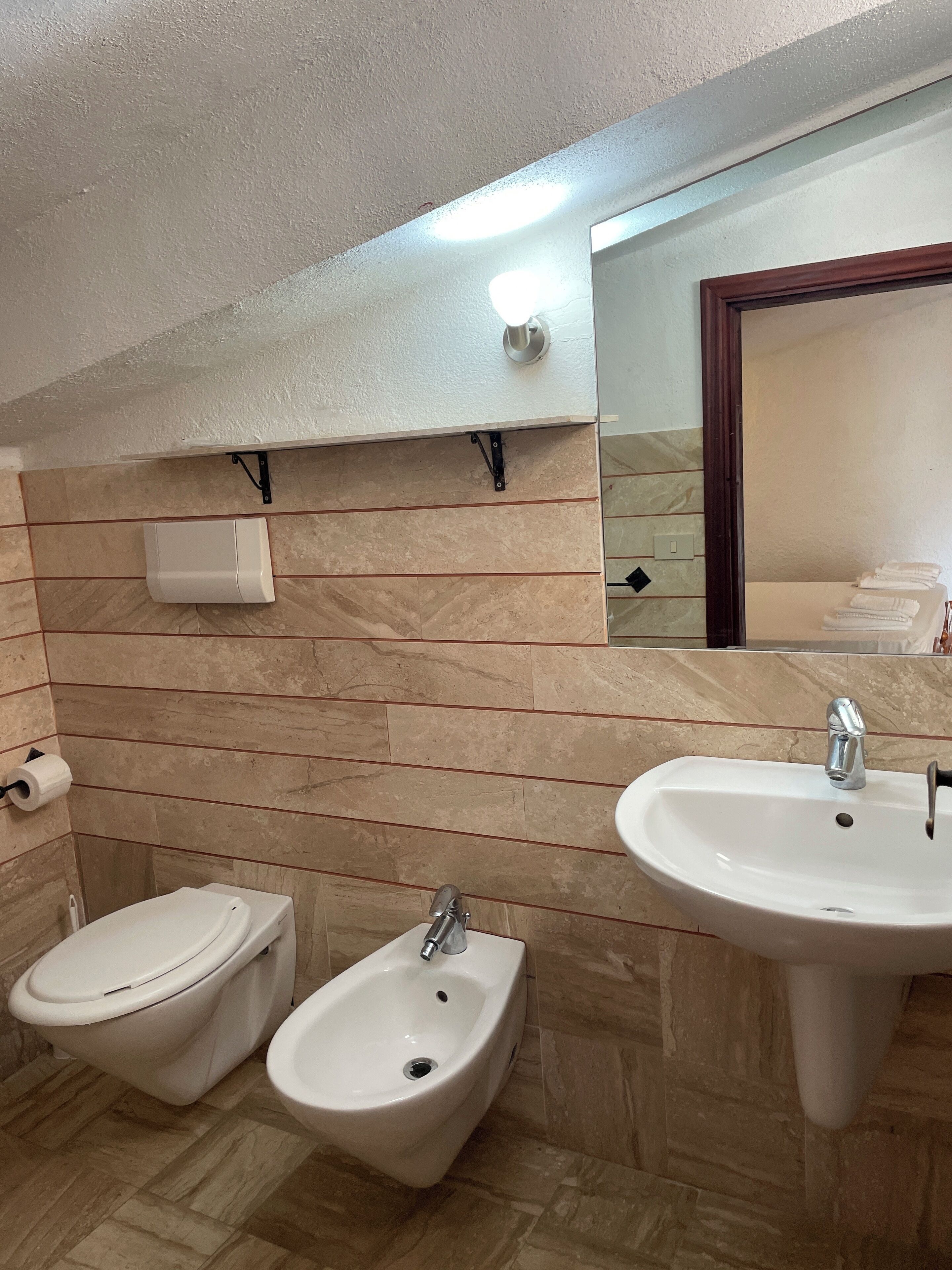 Un baño con bidé, lavabo e inodoro.