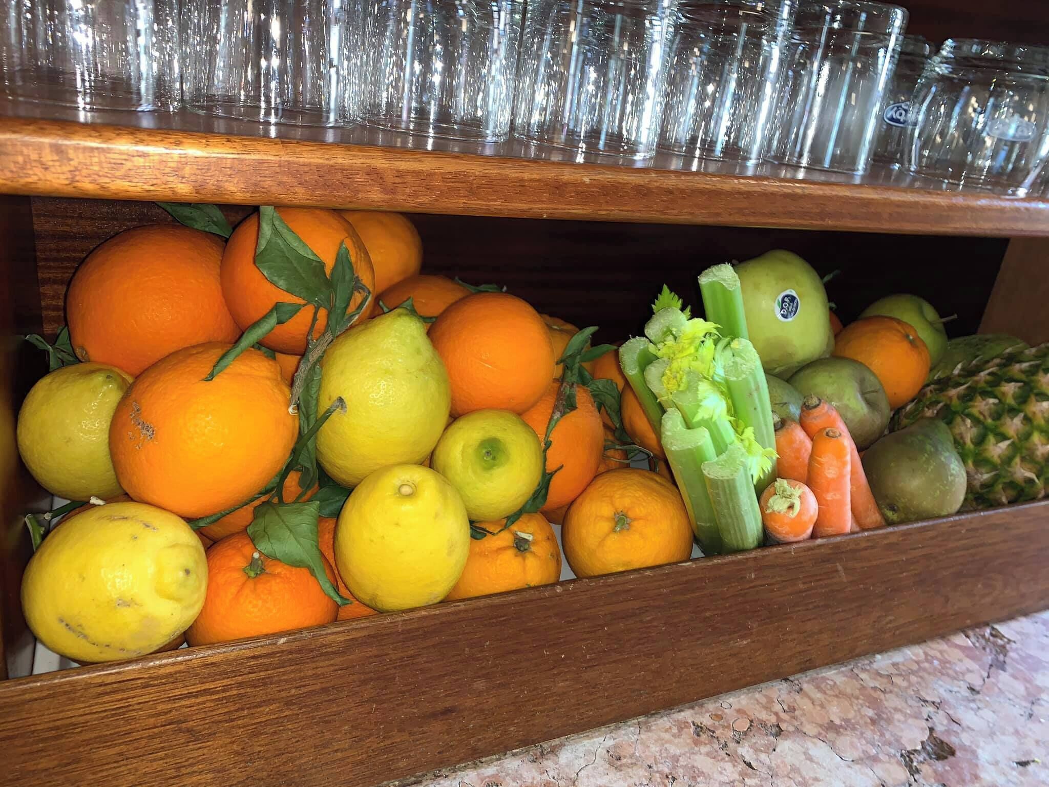 Een houten lade gevuld met sinaasappels, citroenen, bleekselderij en ander fruit.