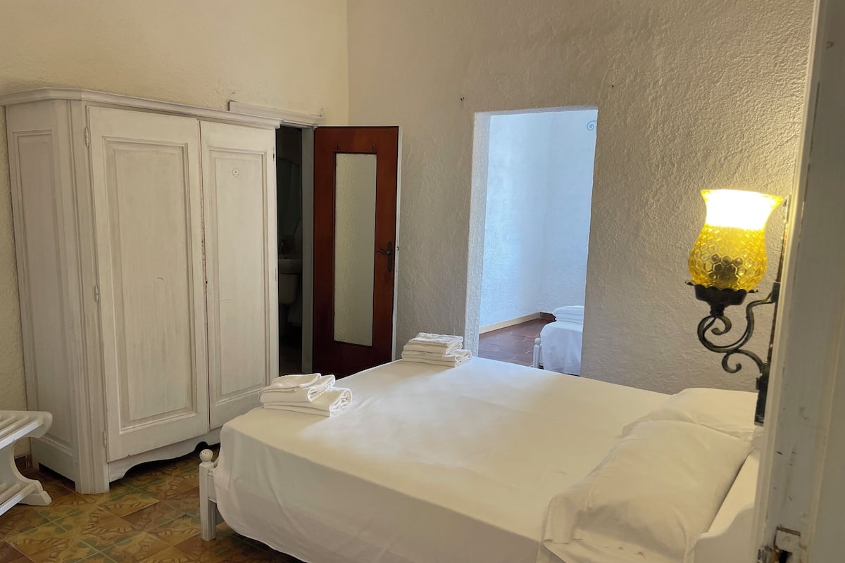 Ein Schlafzimmer mit Bett, Kleiderschrank, Spiegel und Fenster mit Aussicht.