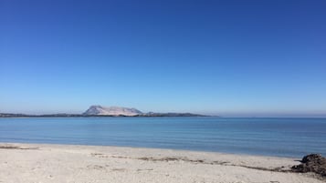 A beach with a mountain in the distance and a clear blue sky.