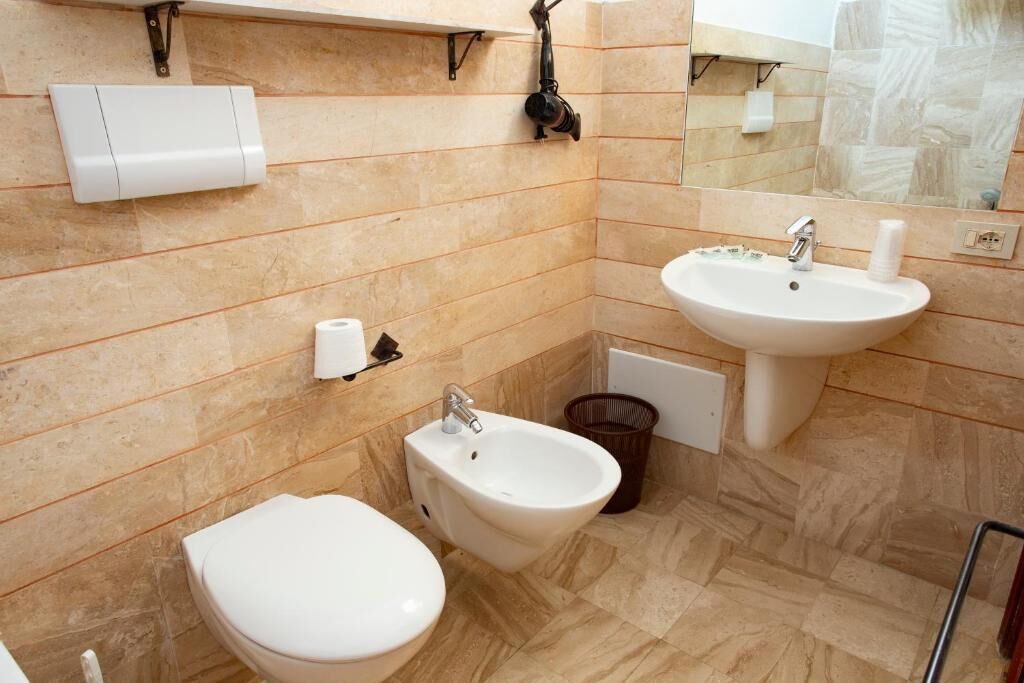 Une salle de bain équipée de toilettes, d’un bidet, d’un lavabo et d’un miroir.