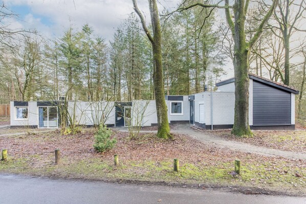 A row of cabins with a covered outdoor area, surrounded by trees. - Veluwe Forest Bungalow (Kootwijk)