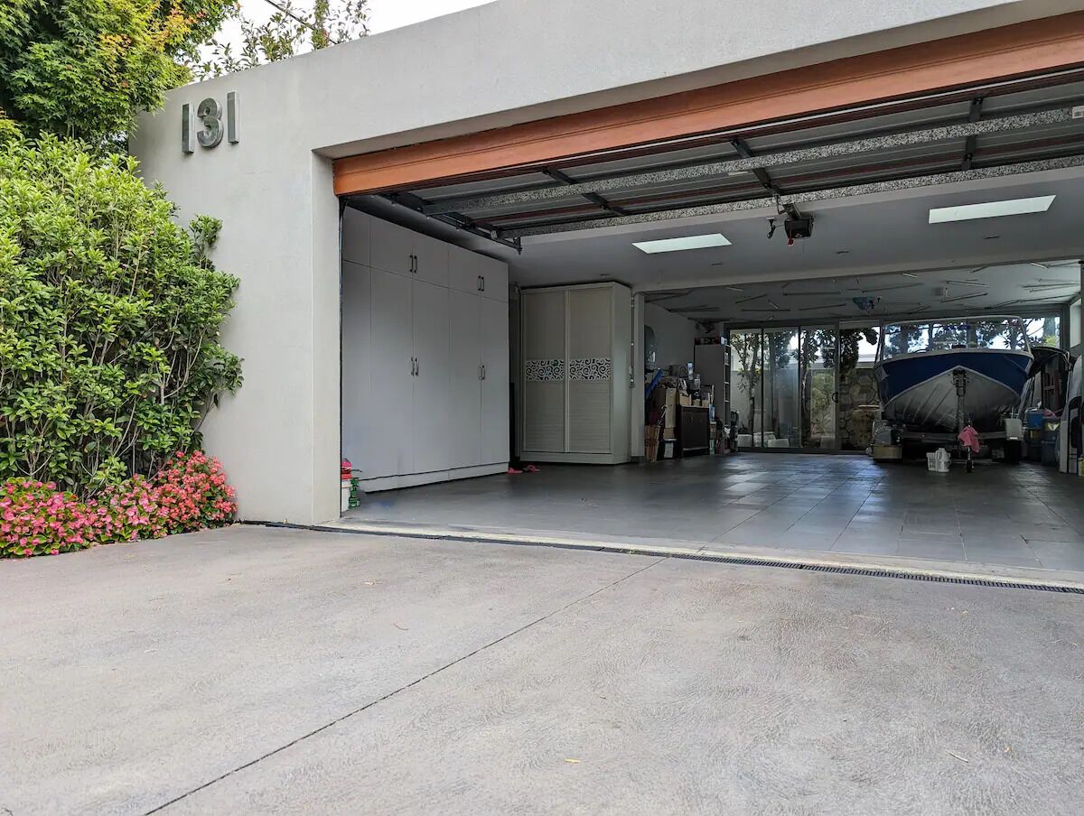 A garage entrance with a number '131' sign, a concrete floor, and a boat parked inside.