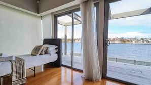 A bedroom with a bed, a window with a view of the water, and a balcony. - Waterfront Oasis - Panoramic Views | Infinity Pool (Kogarah Bay)