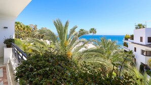 A balcony with a view of the sea, surrounded by palm trees and white buildings. - Doncella Beach luxury with ocean view (Estepona)