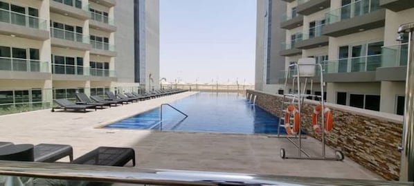 A swimming pool with lounge chairs and a lifeguard stand in a modern building.