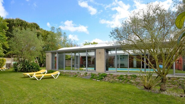 A modern house with a glass-enclosed patio, a swimming pool, and a well-maintained lawn with lounge chairs. - La belle étape by Interhome (Cherrueix)