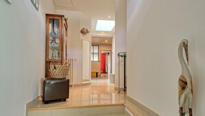 A hallway with a staircase, a wooden bench, a glass cabinet, and a decorative bird sculpture. - La belle étape by Interhome (Cherrueix)