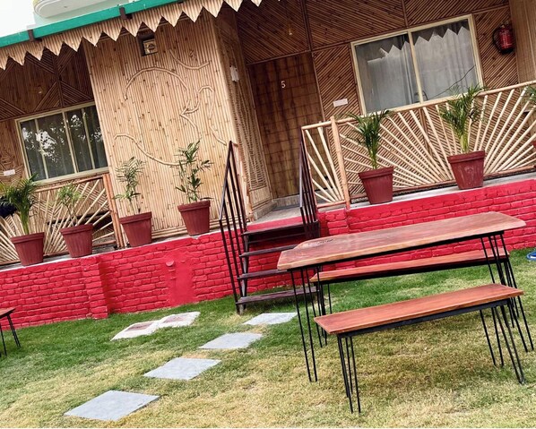 A wooden building with a red brick wall, a wooden deck, and outdoor seating with benches and chairs.