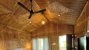 A room with a bed, a ceiling fan, a TV, and wooden walls.