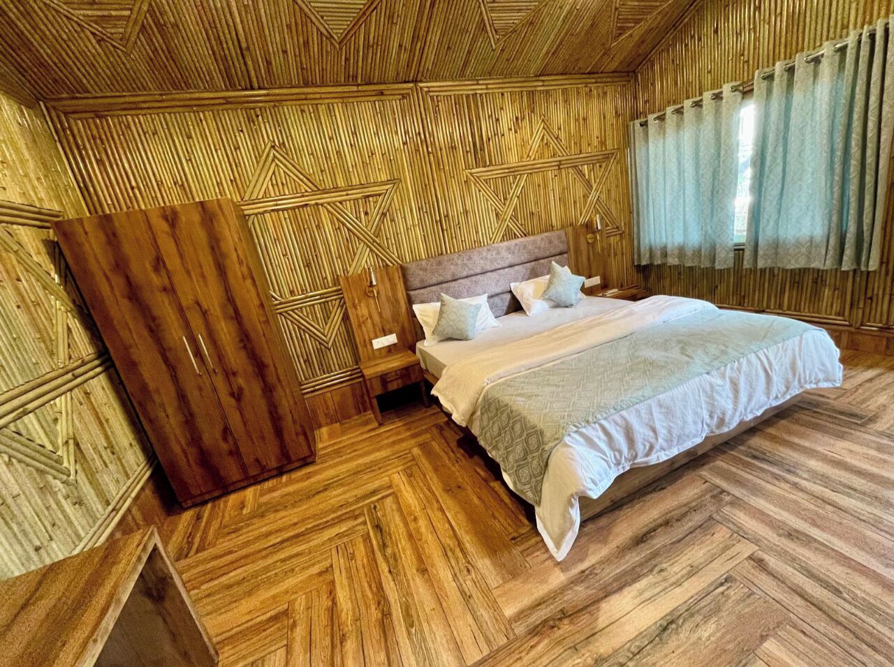 Une pièce avec un lit, des murs en bois et un parquet à motifs en chevrons.