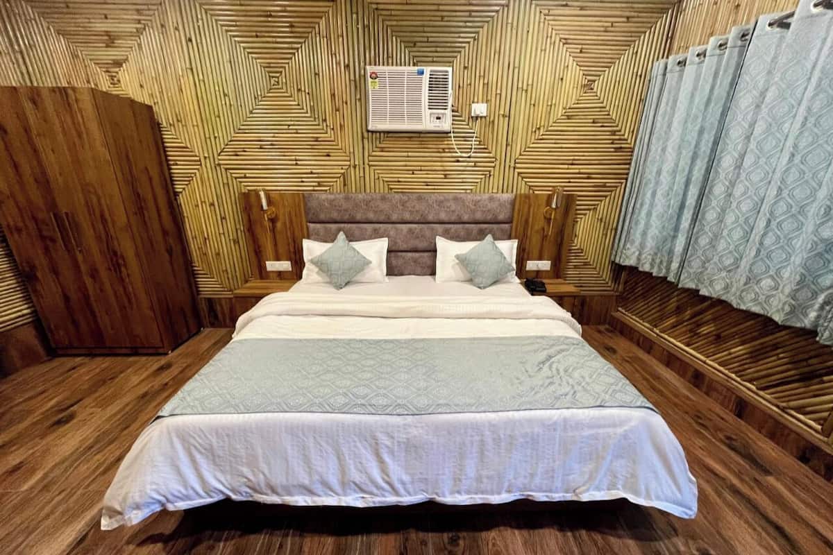 Un dormitorio con cabecera de madera, cama con dos almohadas y armario de madera.