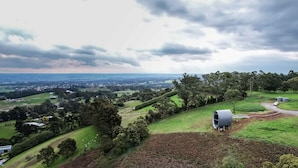 A rural landscape with a large open field, a small building, and a distant town. - The Skybarrel (Buninyong)
