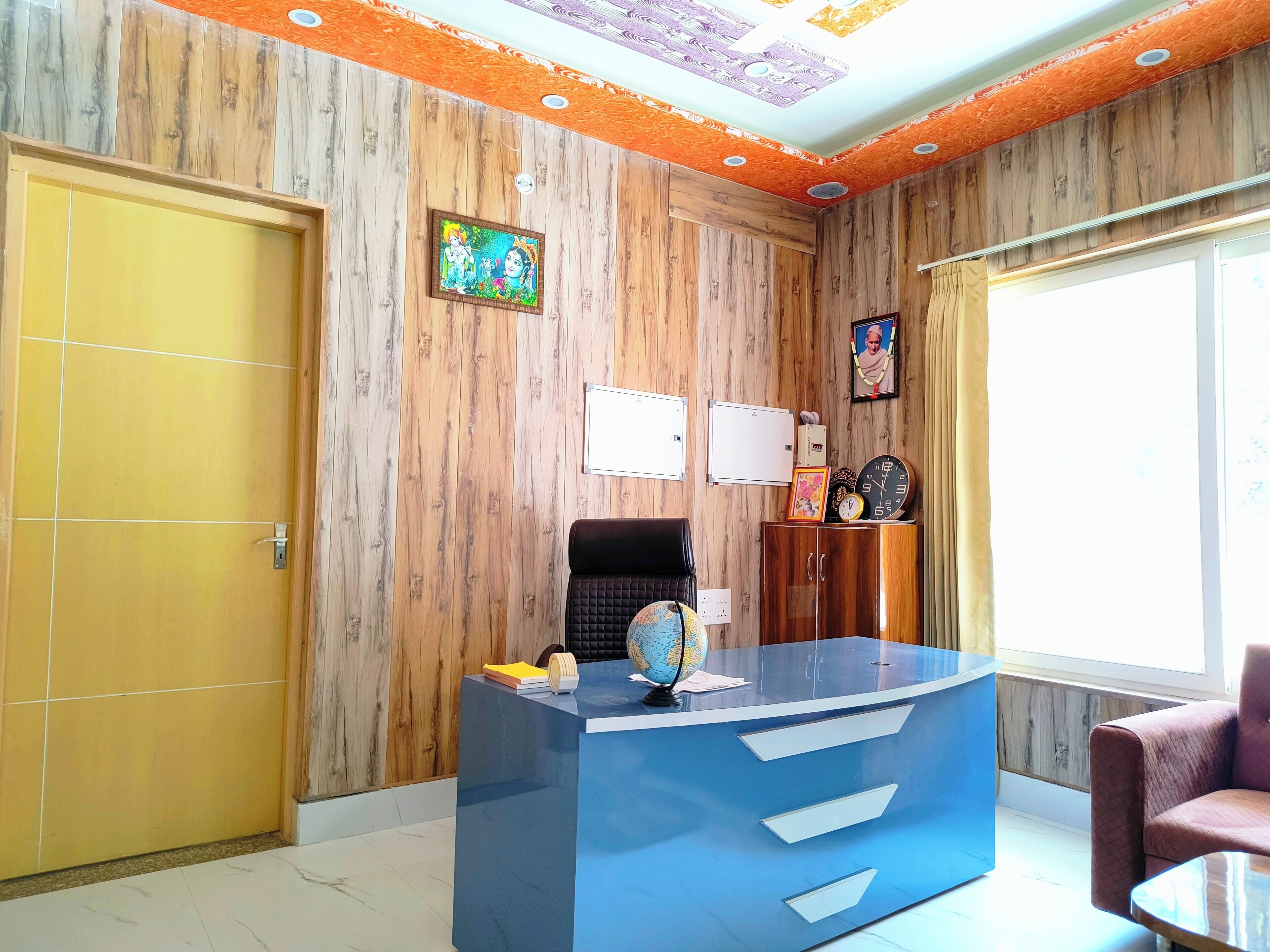 Un área de recepción con un escritorio azul, un globo terráqueo y un reloj.