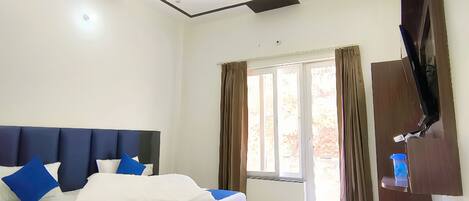 A modern bedroom with a large bed, a ceiling fan, and a TV mounted on the wall.