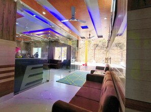 A modern hotel lobby with a reception desk, seating area, and a view of the outdoors. - Hotel Hill River View Resort (Dunda)