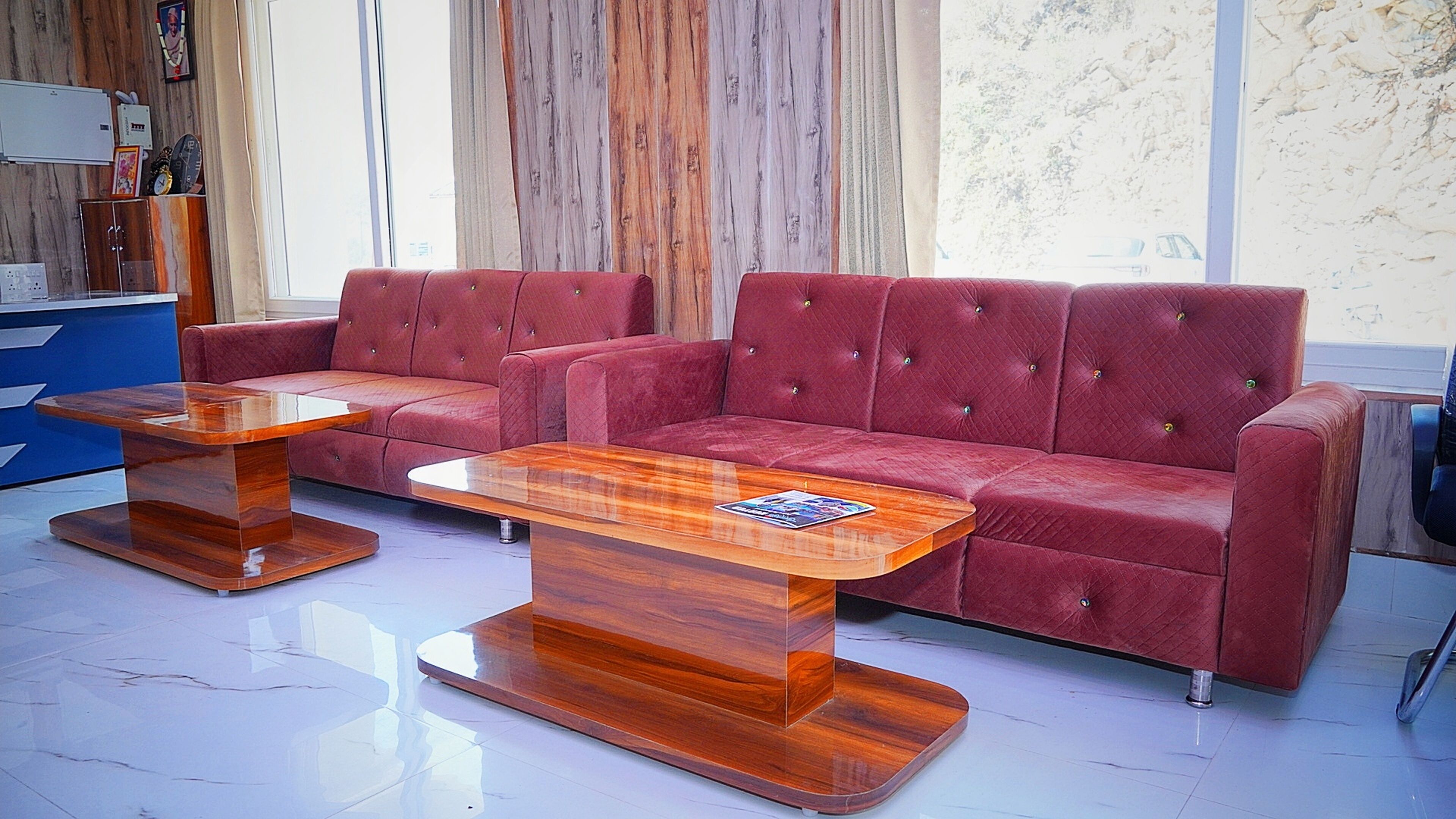 A red sofa with a wooden coffee table in a room with a wooden floor and a large window.