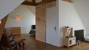 Una camera da letto mansardata accogliente, con travi a vista in legno, un angolo cottura, un armadio in legno e un letto singolo.