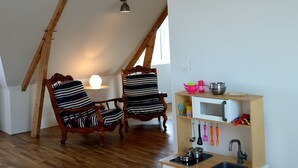 Una stanza in stile loft con travi in legno a vista, angolo cottura, due poltrone a righe e un tavolino con una lampada.