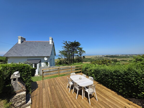 A house with a deck and outdoor seating area, overlooking a scenic landscape.