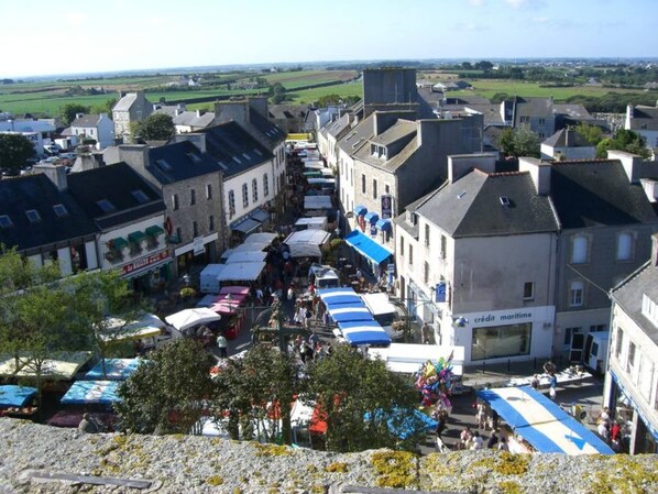 Una piazza cittadina con edifici, un mercato e vista sulla campagna.