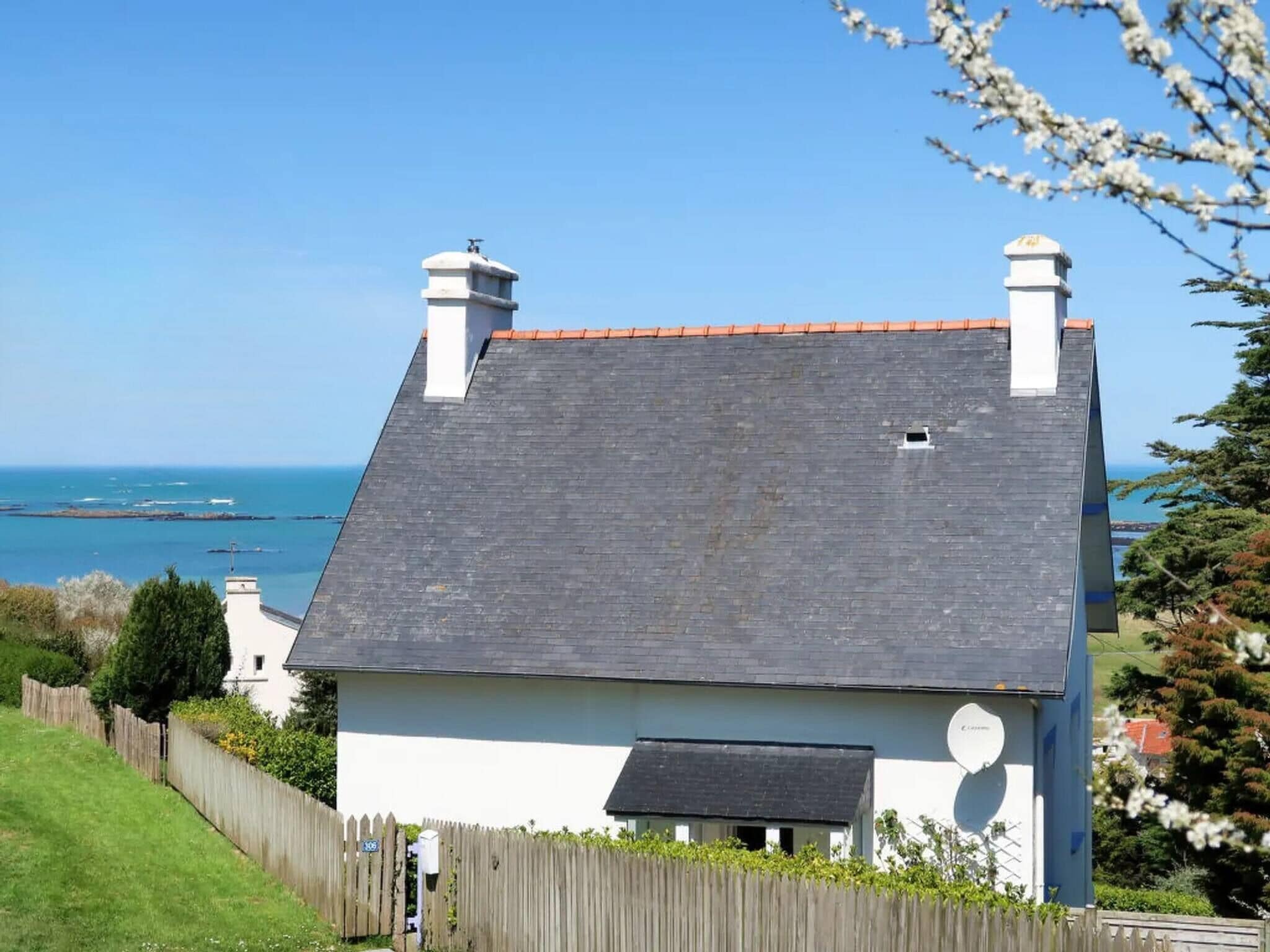 A house with a sloped roof, a chimney, and a view of the sea.