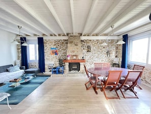 Un vaste espace de vie doté d’une cheminée en pierre, d’une table à manger avec des chaises et d’un canapé.