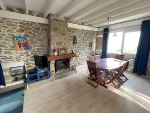 Un coin repas avec une cheminée en pierre, une table ronde et des chaises.
