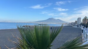 Ein Strand mit einem Berg im Hintergrund, einem klaren Himmel und ein paar Spaziergängern.