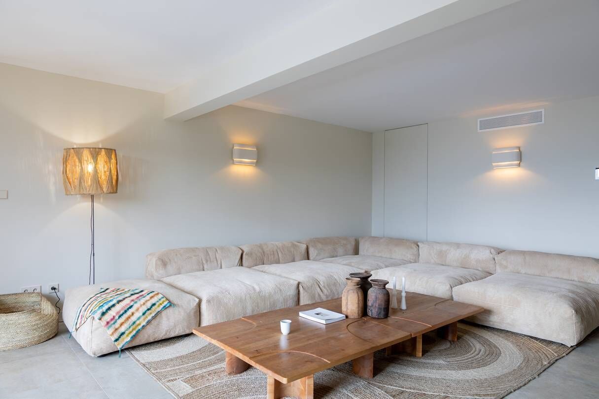 Un salon moderne avec un canapé d’angle, une table basse en bois et un lampadaire.