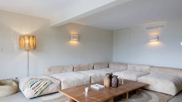 Un salon moderne avec un canapé d’angle, une table basse en bois et un lampadaire.