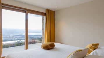 Une chambre avec une grande fenêtre, un lit et une vue sur un paysage.