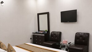 Une chambre à coucher moderne, équipée d’un lit, de deux fauteuils en cuir, d’une commode et d’un téléviseur à écran plat.